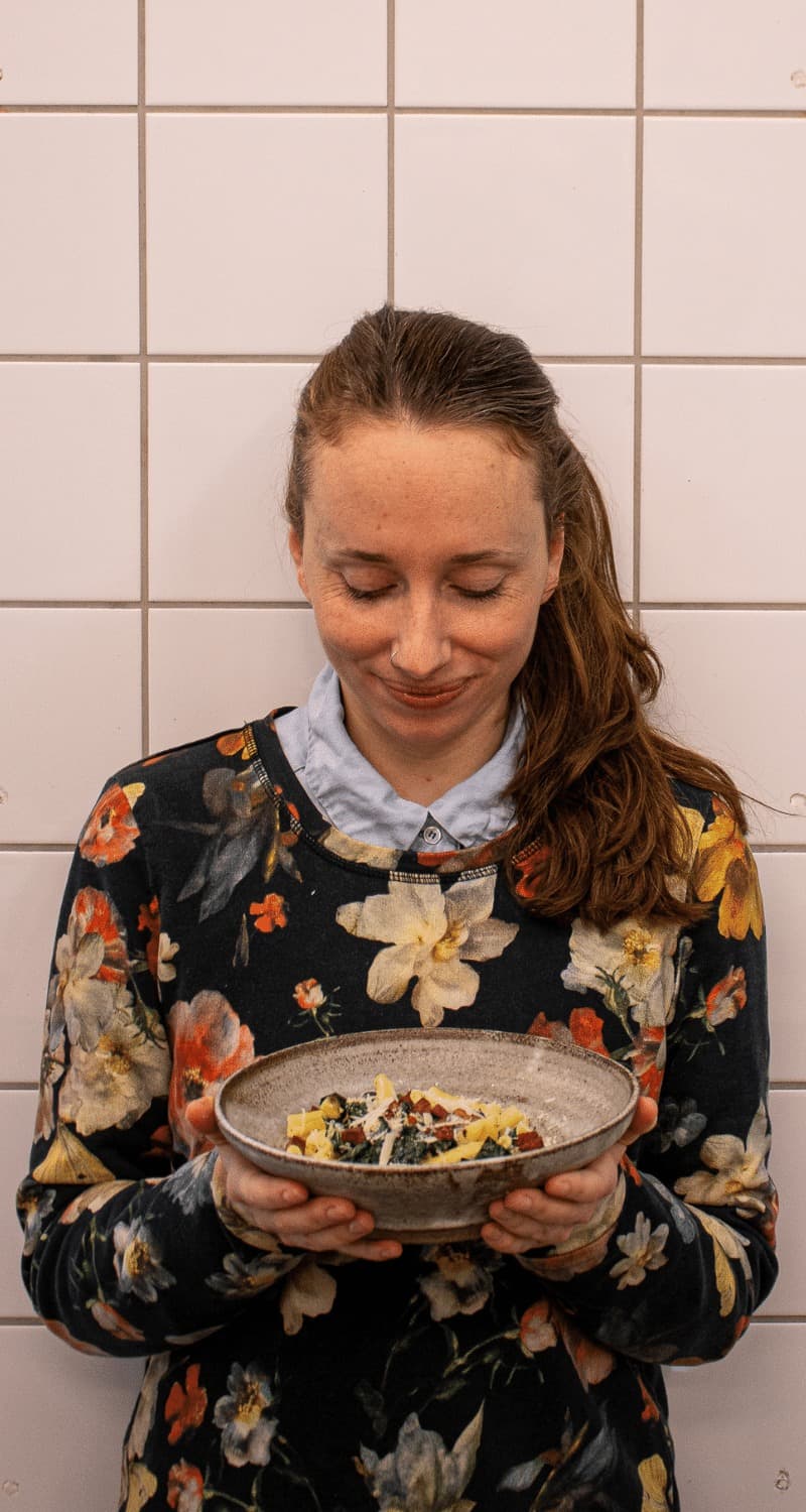 Bilden visar Hanna Olvenmark / Portionen under tian som håller i en skål med svartkålspasta