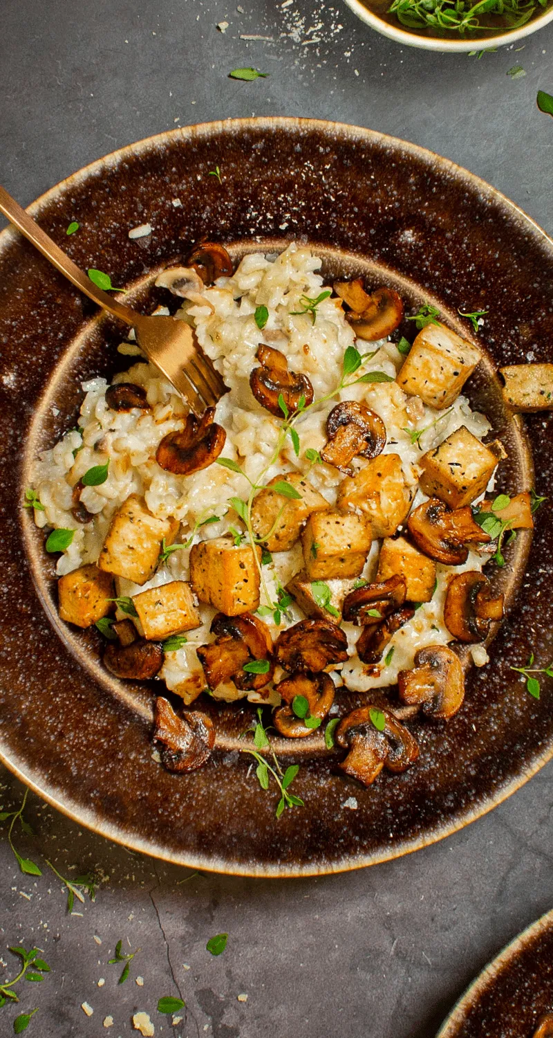 Bilden visar en vegansk risotto med svamp och örtmarinerad tofu