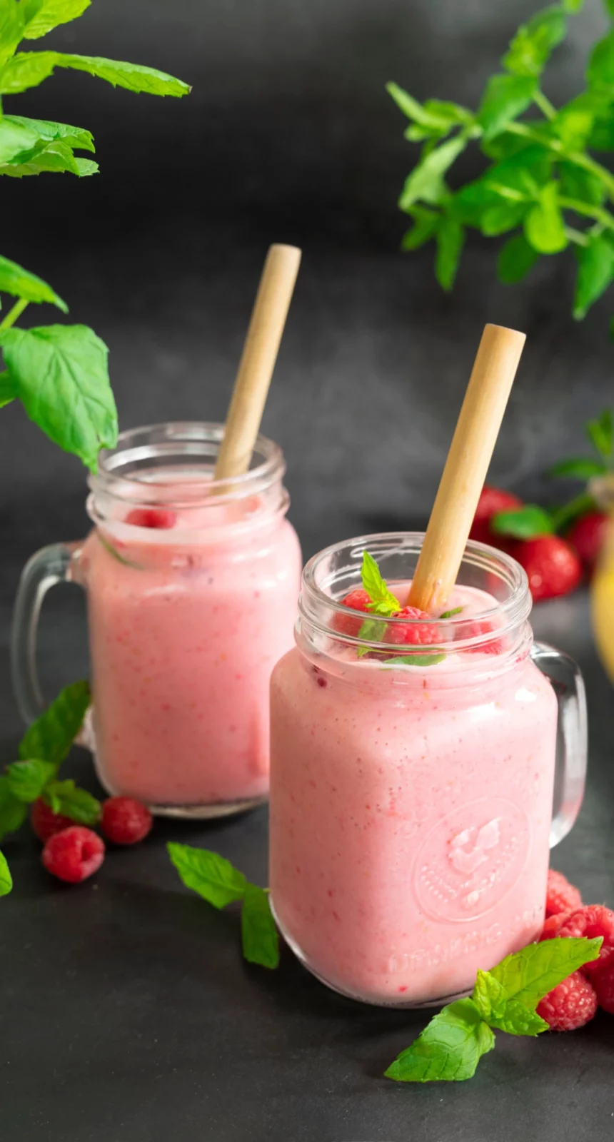 Vegansk smoothie med jordgubb, hallon och banan. Serverad i glas med bambu-sugrör.
