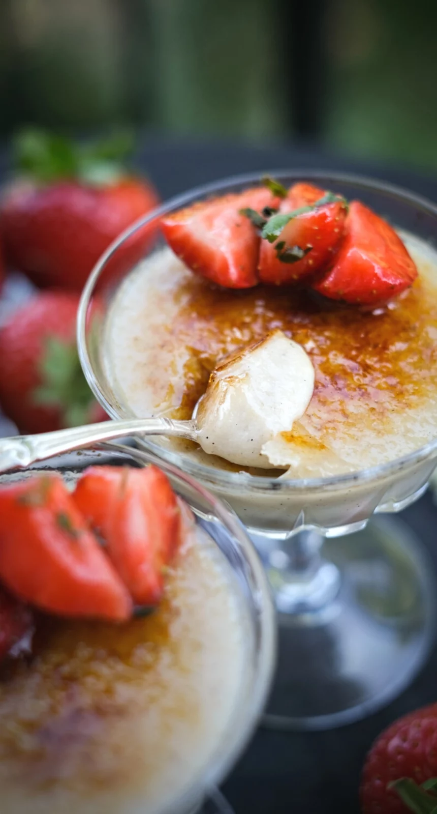 Vegansk creme brulee (vegansk crème brûlée) serverad i dessertglas med jordgubbar och sked.