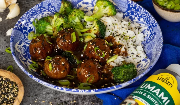 Blå tallrik med köttbullar, med ris och broccoli på sidan. 