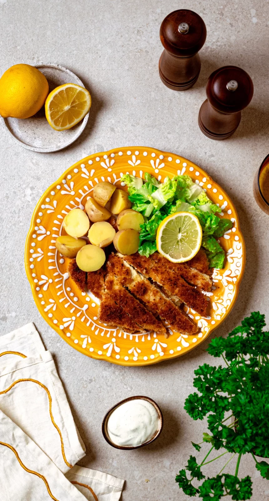 Bilden visar en vegetarisk schnitzel med tofu, potatis, sallad och örtsås.